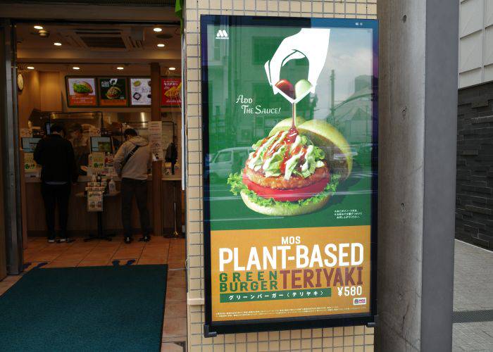 A poster at the front of a Mos Burger, promoting their Green Burger, a vegan burger option.